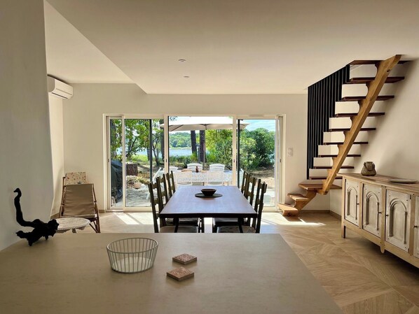A dining area with a table, chairs, and a view through glass doors to an outdoor space.