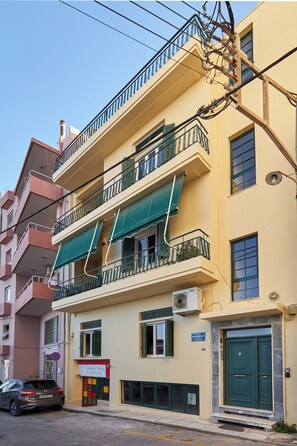 Een meerhoog gebouw met balkons, airconditioning en een groen luifel.