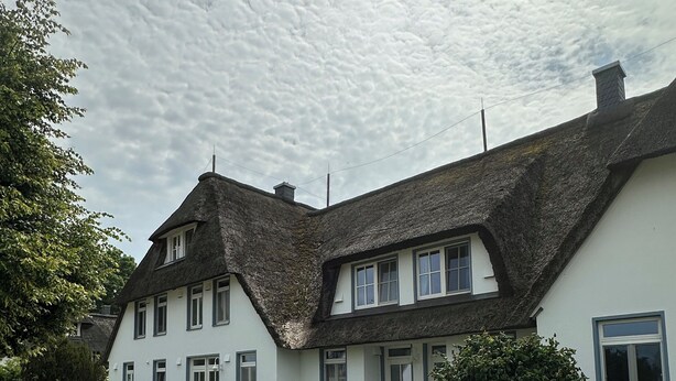 A two-story house with a thatched roof, white walls, and multiple windows. - Landhaus am Haff, Apartment B6 - Vacation under thatch (Stolpe auf Usedom)