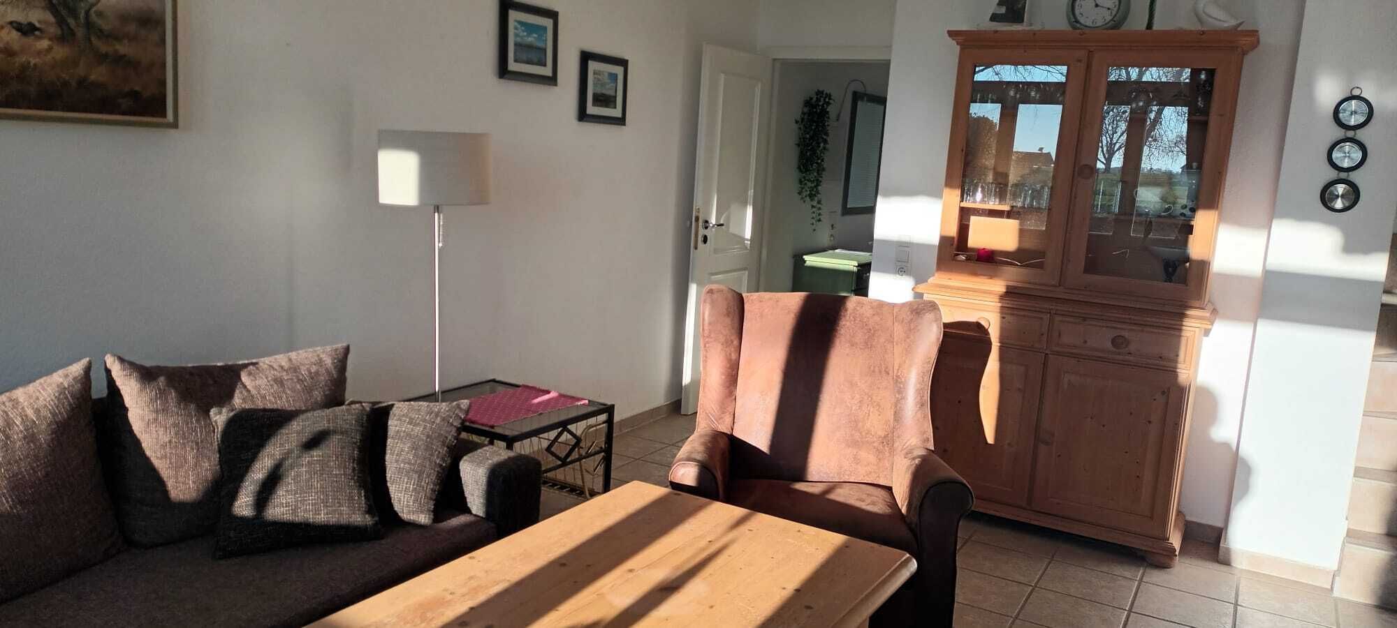 Una sala de estar con un sofá, una mesa de madera y un armario.