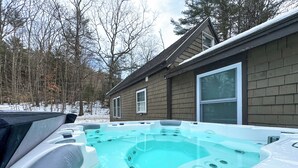 Un jacuzzi en un patio trasero con una casa al fondo.