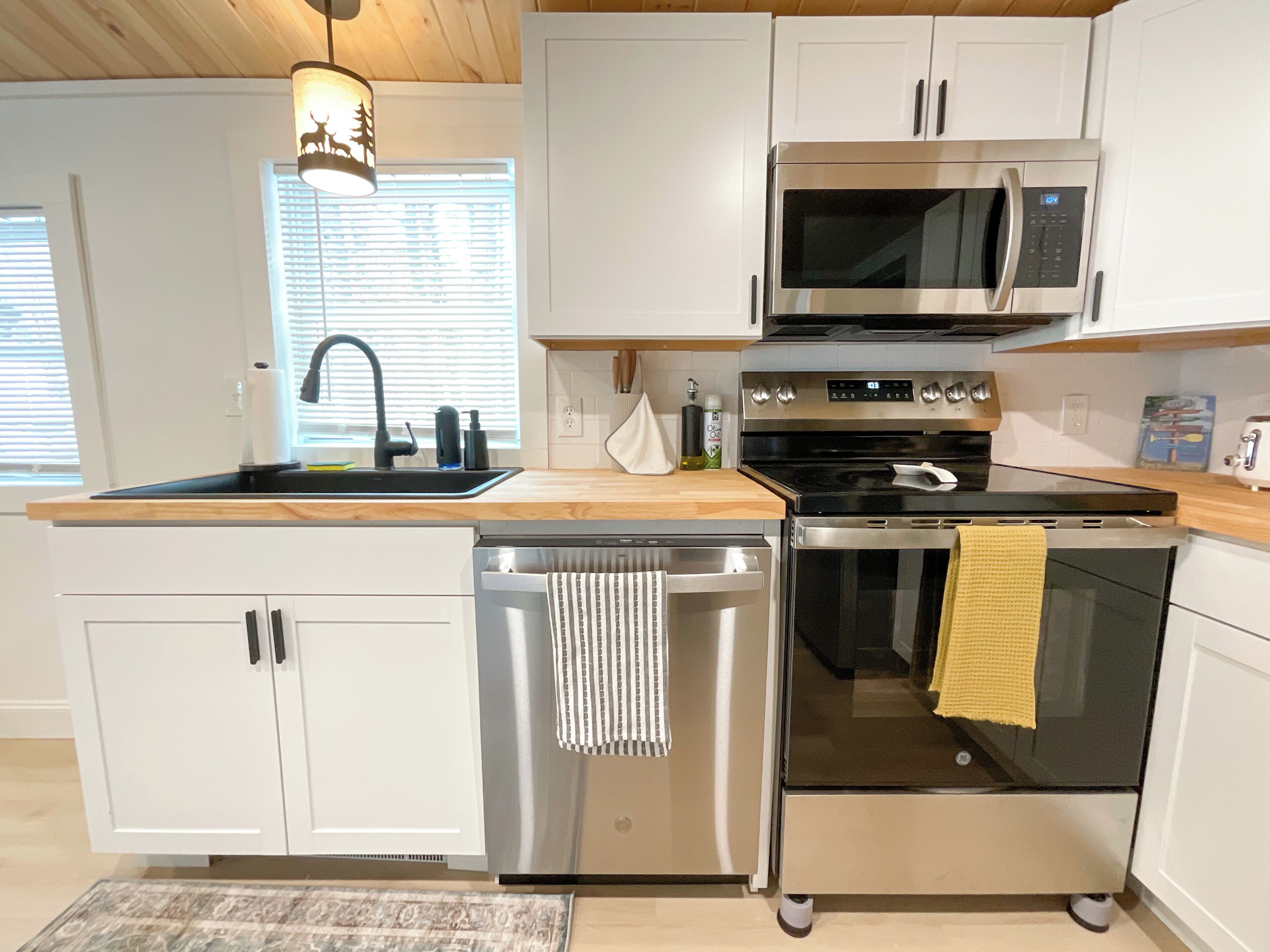 A modern kitchen with white cabinets, stainless steel appliances, a dishwasher, and a microwave.