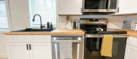 A modern kitchen with white cabinets, stainless steel appliances, a dishwasher, and a microwave.