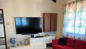 Ein modernes Wohnzimmer mit Flachbildfernseher, einem roten Sofa, einem Couchtisch und einer weißen Unterhaltungseinheit.