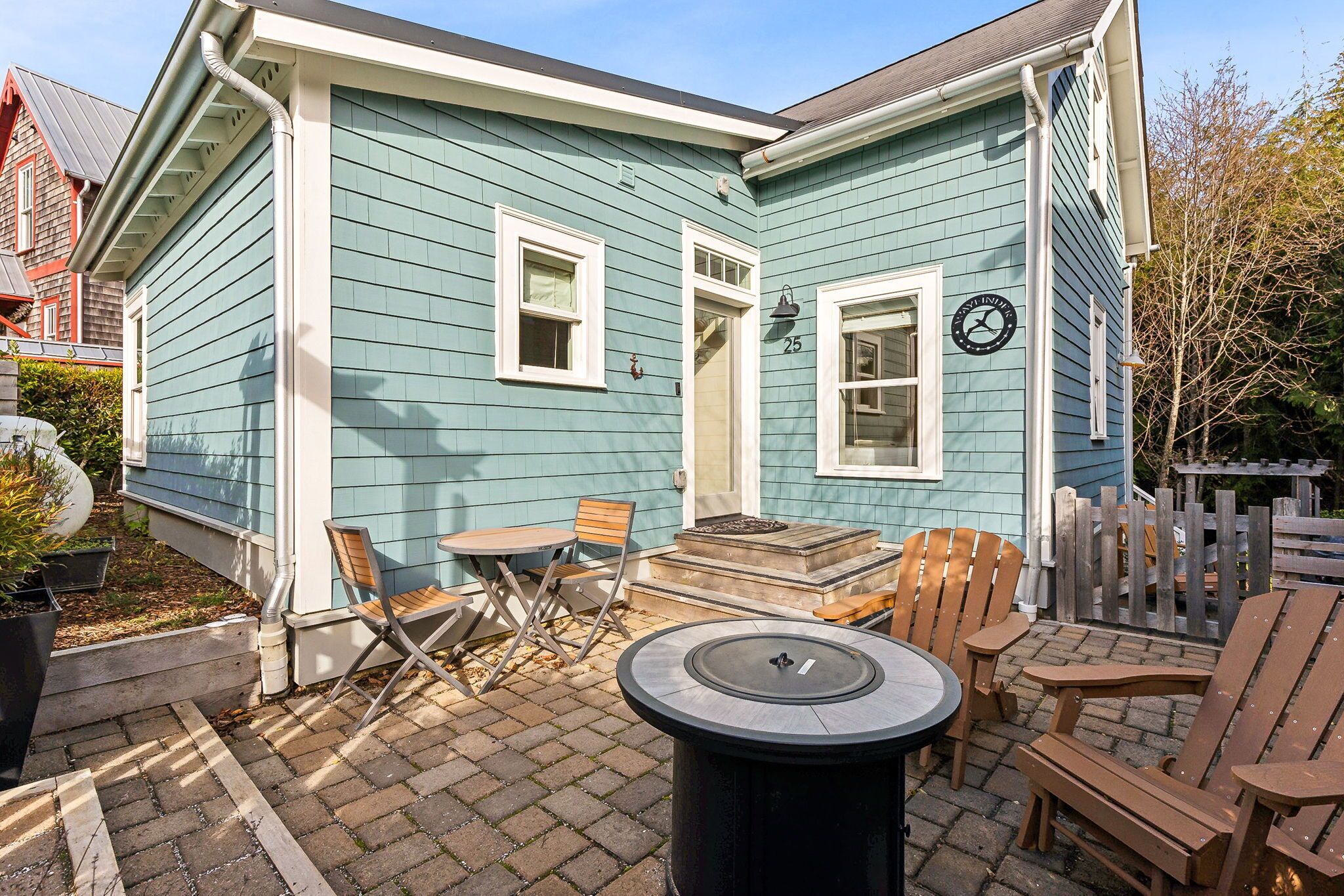 Une maison bleue dotée d’un patio comprenant une table, des chaises et un foyer.