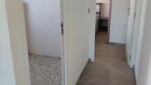 A narrow hallway with a tiled floor leading to a room with a shower. - Apartment 7 minutes from Porto Vecchio (Porto-Vecchio)