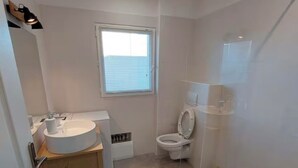 A compact bathroom with a sink, toilet, and shower area. - Apartment 7 minutes from Porto Vecchio (Porto-Vecchio)