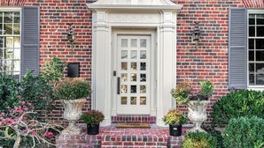 A brick building with a white door, decorative elements, and potted plants. - Grand 5200 sf Home, Wesley Heights, 4BR 3.5BA (Washington)
