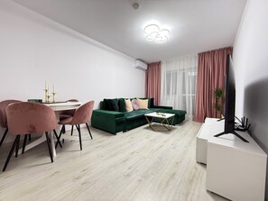 Relax in this stylish living space with a green sofa, round dining table, and flat-screen TV.