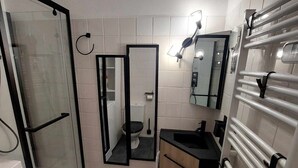 Une salle de bain moderne avec une douche à parois de verre, des toilettes, un lavabo et un miroir.