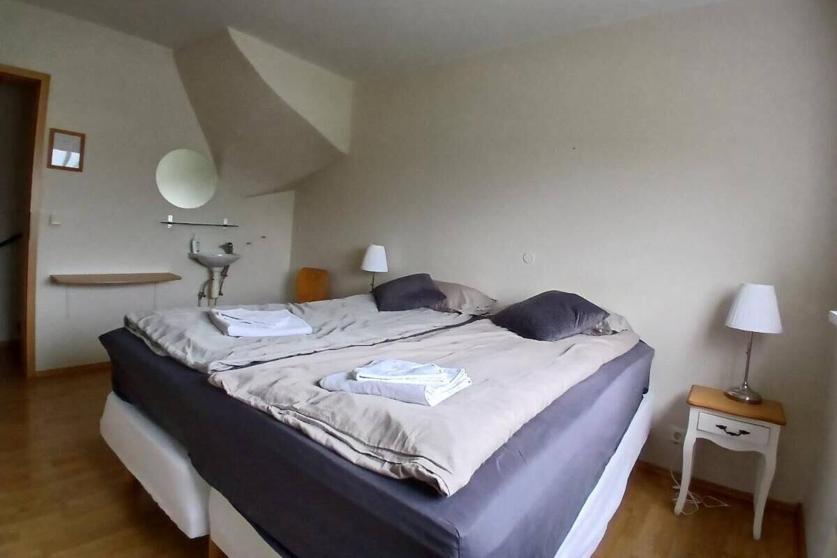 Une chambre à coucher avec un lit, des tables de chevet, un miroir et un lavabo.