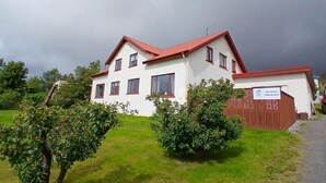 A two-story building with a red roof and white walls, labeled as a guesthouse.
