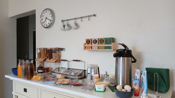 A kitchen counter with various food items, a kettle, and a clock on the wall.