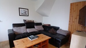 A modern living room with a black leather sofa, a wooden coffee table, and a framed picture on the wall.