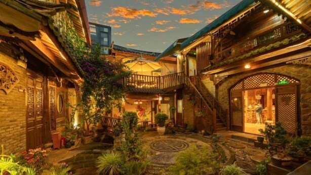 A traditional courtyard with potted plants, a central fountain, and a wooden staircase. - Dayetang Private Shangpin Inn (Lijiang) (Lijiang)