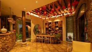 A cozy lobby with a wooden floor, a reception desk, a dining area, and a bookshelf filled with books and decorative items. - Dayetang Private Shangpin Inn (Lijiang) (Lijiang)