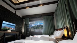 A hotel room with a bed, two sofas, a TV, and a view of a mountainous landscape. - Dayetang Private Shangpin Inn (Lijiang) (Lijiang)
