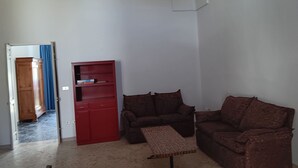 A living room with a red bookshelf, two patterned sofas, and a small table. - Casetta Rita in Melpignano (Melpignano)