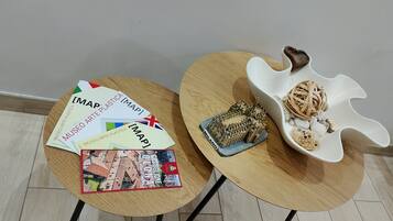 Two round tables with different designs, one with a book and brochures, and the other with a decorative item and a small model.