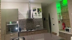A modern kitchen with a built-in oven, a stainless steel range hood, and a microwave. - Orchid Apartment (Castiglione Olona)