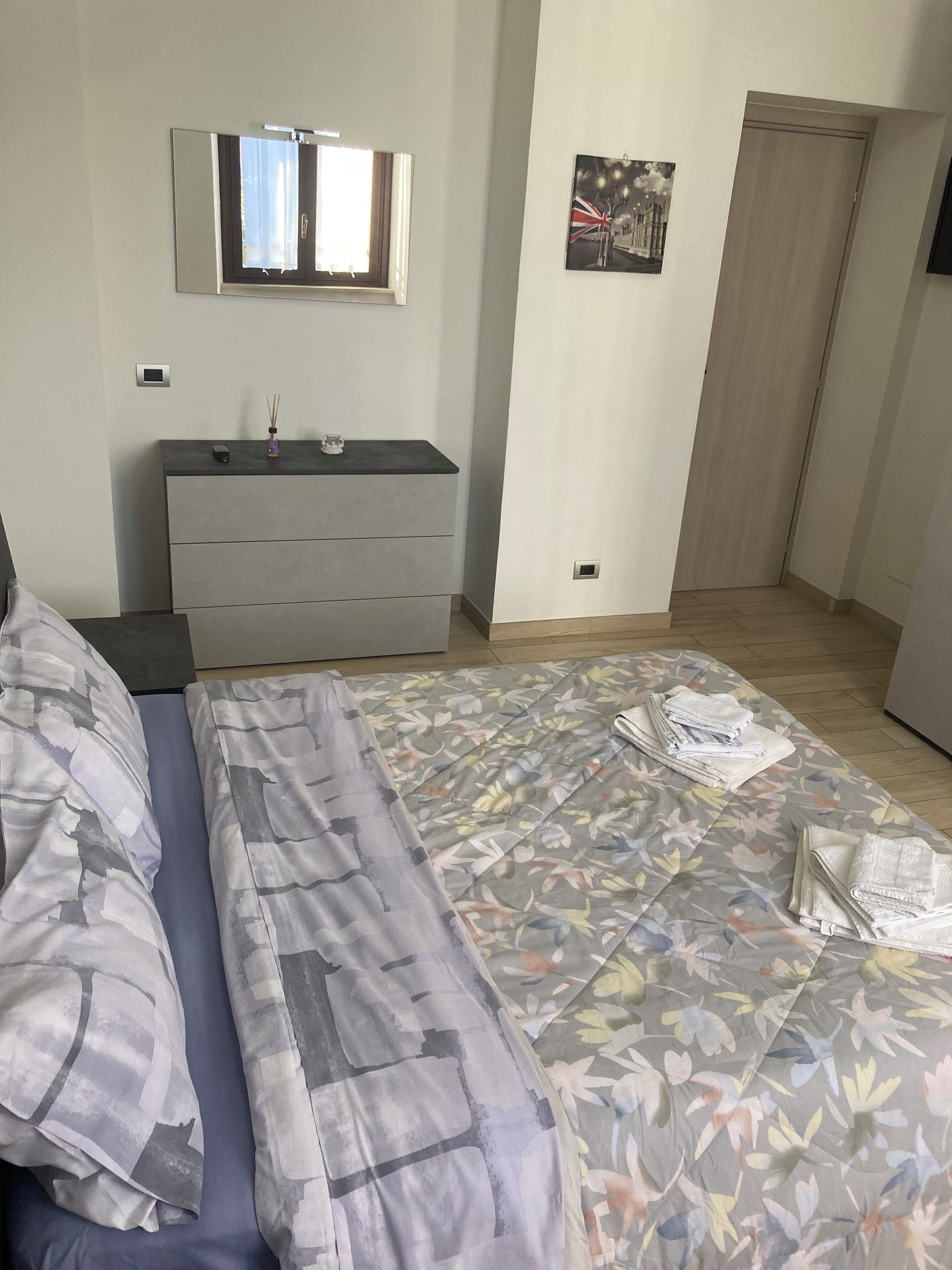 Una camera da letto con un letto, una cassettiera, uno specchio e una porta.