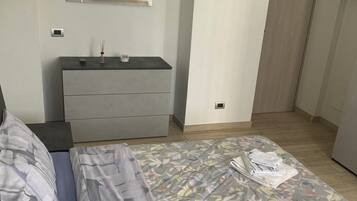 Una camera da letto con un letto, una cassettiera, uno specchio e una porta.
