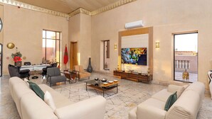 A spacious living room with a marble floor, a large flat-screen TV, and a sofa set. - Palais Nouhass (Marrakech)