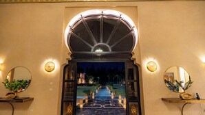 An arched entrance with a chandelier, a marble floor, and two side tables with plants. - Palais Nouhass (Marrakech)