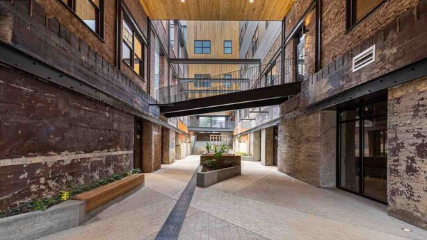 A spacious indoor area with a high ceiling, exposed brick walls, and a central open space with planters. - #302 New Downtown Condo on Morris Ave (Birmingham)