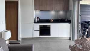 A modern kitchen with white cabinets, a black countertop, and a built-in oven. - Waterfront apartment, Porto-Vecchio (Porto-Vecchio)