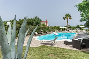 Een seizoensgebonden buitenzwembad en ligstoelen