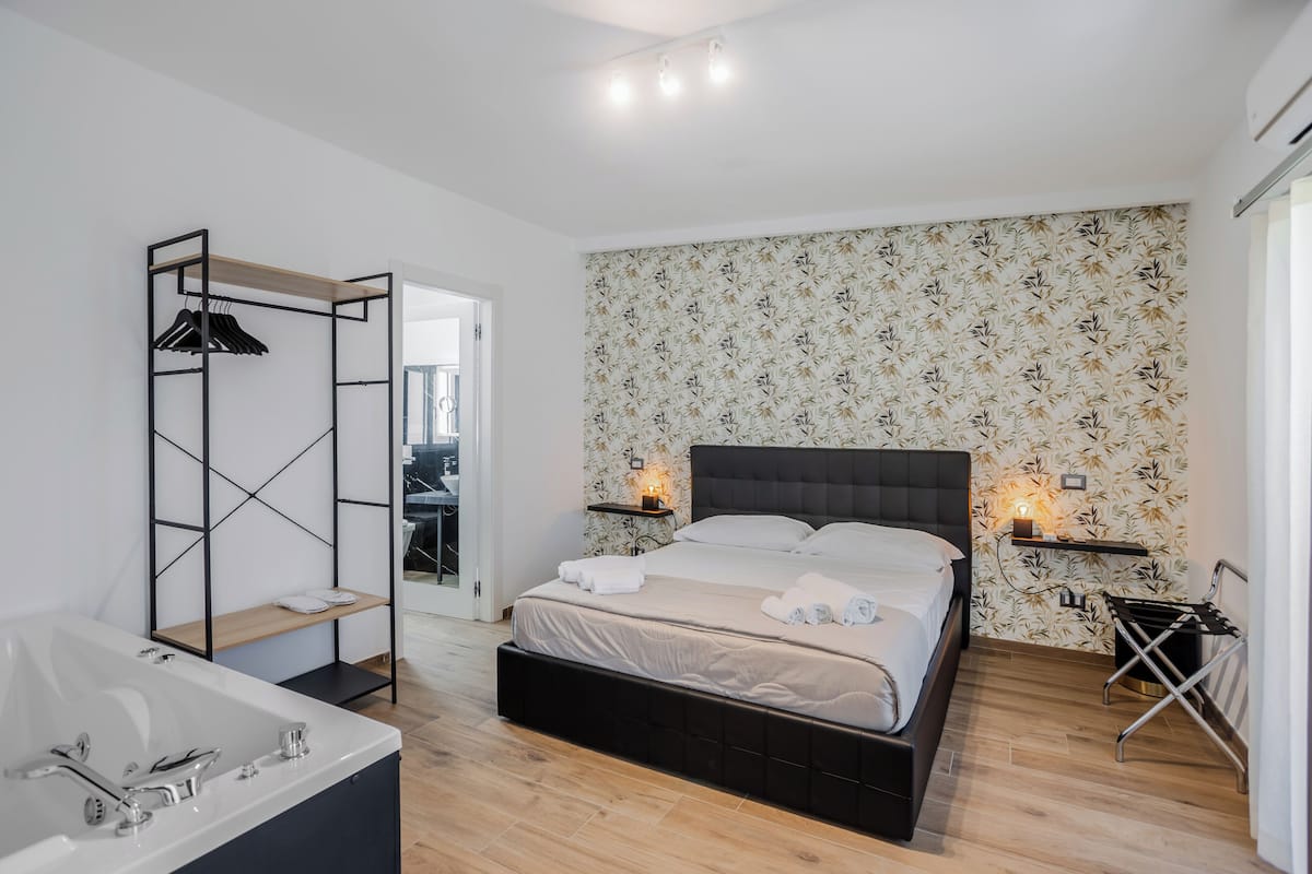 A modern bedroom with a large bed, a separate bathroom, and a wooden floor.
