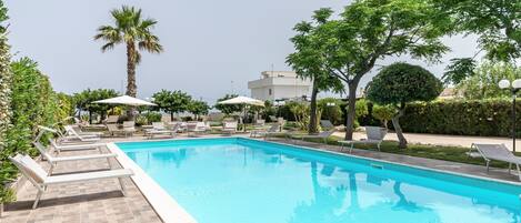 Een seizoensgebonden buitenzwembad en ligstoelen