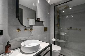 Bathroom features a large round sink, toilet, and glass-enclosed shower.