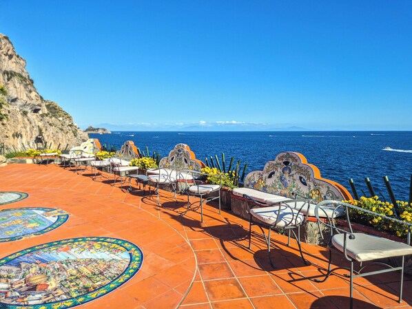 A terrace with outdoor seating, a tiled floor, and a view of the sea. - Villa Costa degli Dei  (Furore)
