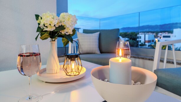 A table with a candle, a glass of red wine, and a vase of white flowers. - Two-bedroom apartment with a terrace (Novalja)