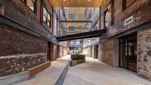 Un vaste espace intérieur doté d’un haut plafond, de murs en briques apparentes et d’un espace central ouvert agrémenté de jardinières.
