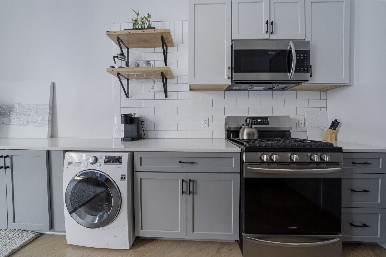 A modern kitchen with a stainless steel stove, a built-in oven, a washing machine, and a microwave.