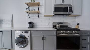 A modern kitchen with a stainless steel stove, a built-in oven, a washing machine, and a microwave.