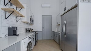 Une cuisine compacte équipée d’un lave-linge, d’une machine à café et d’un réfrigérateur.