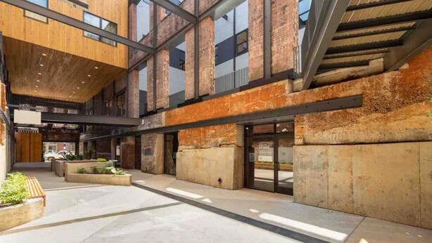 Un vaste patio intérieur doté d’une architecture moderne, qui combine des éléments en bois et en brique, et qui comprend un espace central ouvert avec des sièges.