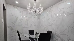 A dining area with a marble wall, a chandelier, and a table with four chairs. - Charming and Cozy Place (Las Vegas)