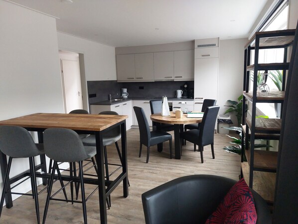 A modern kitchen with white cabinets, a wooden dining table, and black chairs.