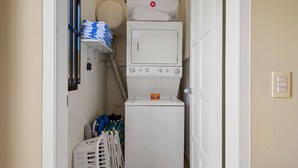 A laundry area with a washing machine, a dryer, and a stack of folded towels. - Luxurious 2-Bedroom Condo near Eagle Beach - Noord (Noord)
