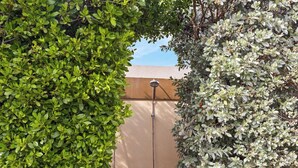 A garden area with a metal fence, a water feature, and dense foliage. - Luxurious 2-Bedroom Condo near Eagle Beach - Noord (Noord)