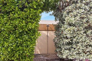 A garden area with a metal fence, a water feature, and dense foliage. - Luxurious 2-Bedroom Condo near Eagle Beach - Noord (Noord)