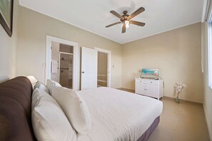 A bedroom with a bed, a ceiling fan, a wardrobe, and a door leading to a bathroom. - 2BR Townhouse w/ Pool View, 1 Min to Eagle Beach (Noord)