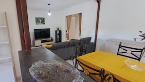 Ett modernt vardagsrum med en soffa, en tv och en matplats med ett gult bord.