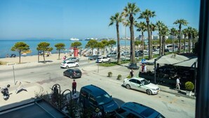 A coastal street with parked cars, palm trees, and a view of the sea. - Adore Boutique Hotel (Vlorë)