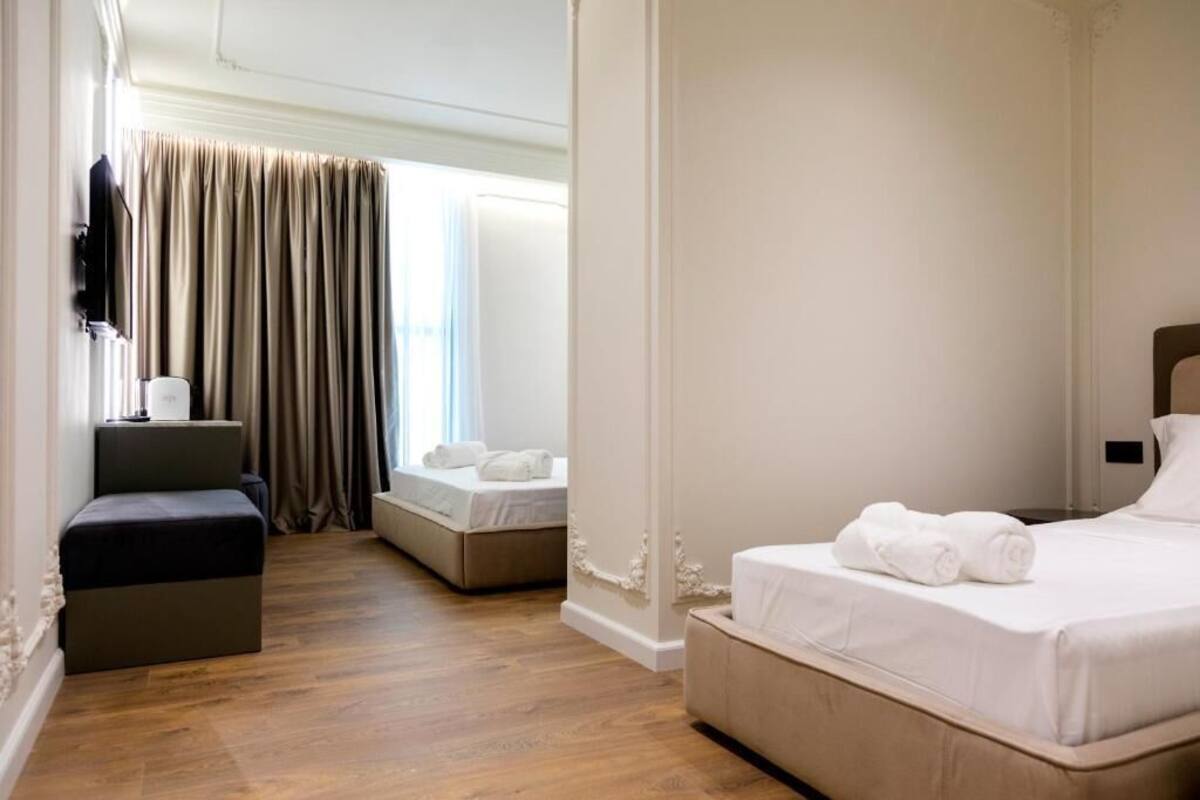 A hotel room with a bed, a seating area, and a window with curtains.